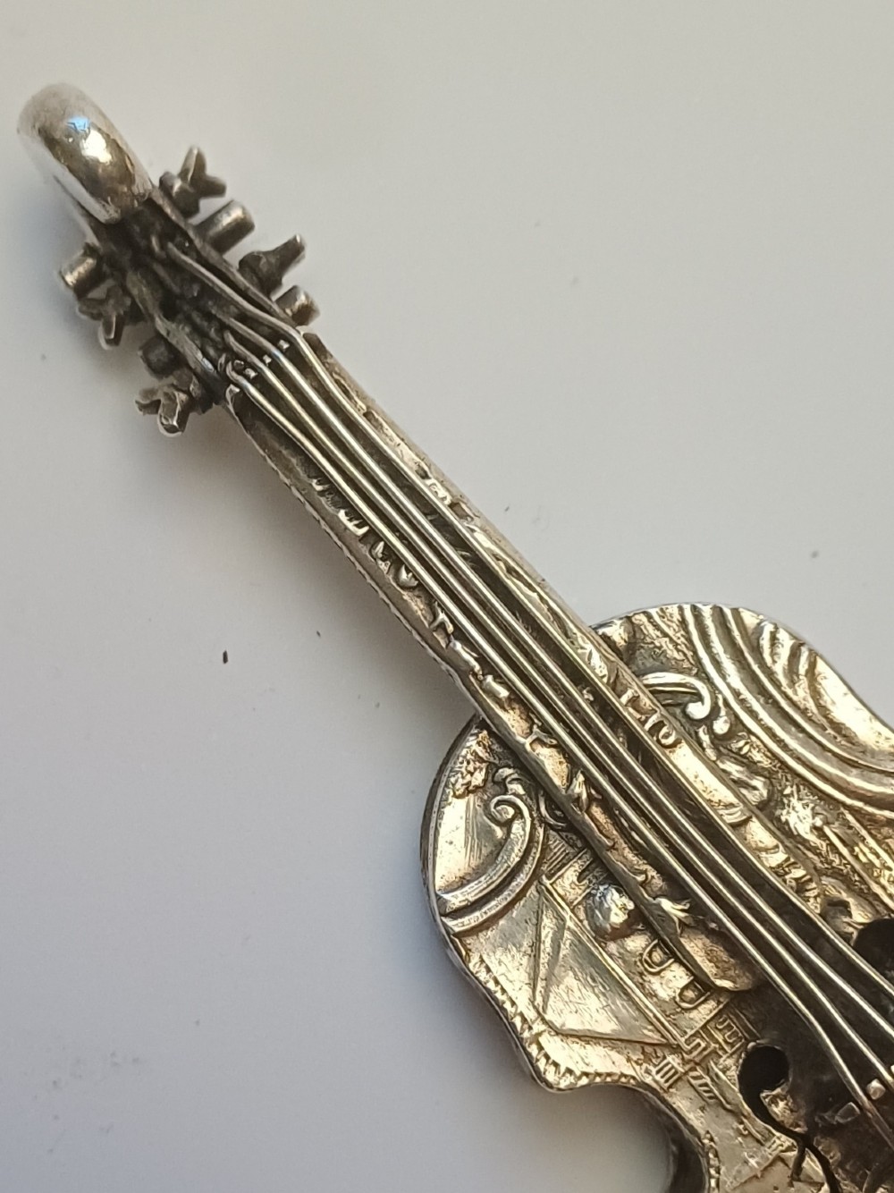 A miniature 19th-century Dutch silver scent bottle crafted in the shape of a violin with engraved scenes and silver wire strings. View VI