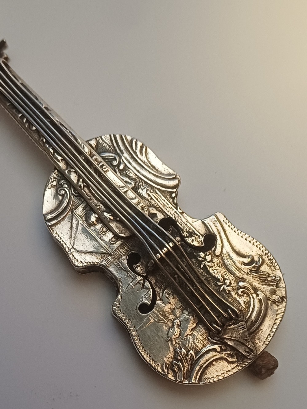 A miniature 19th-century Dutch silver scent bottle crafted in the shape of a violin with engraved scenes and silver wire strings. View VIII