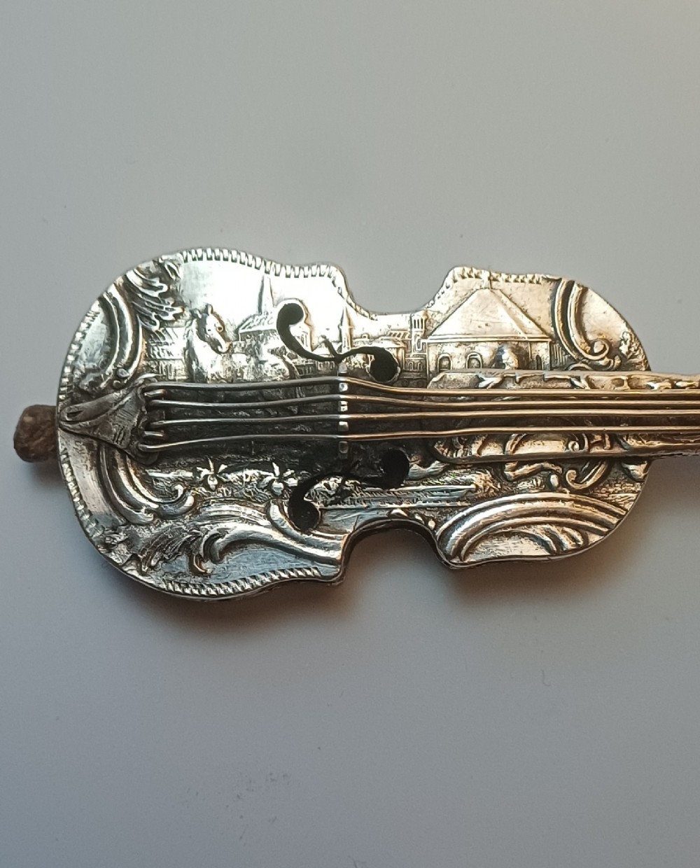 A miniature 19th-century Dutch silver scent bottle crafted in the shape of a violin with engraved scenes and silver wire strings. View IX