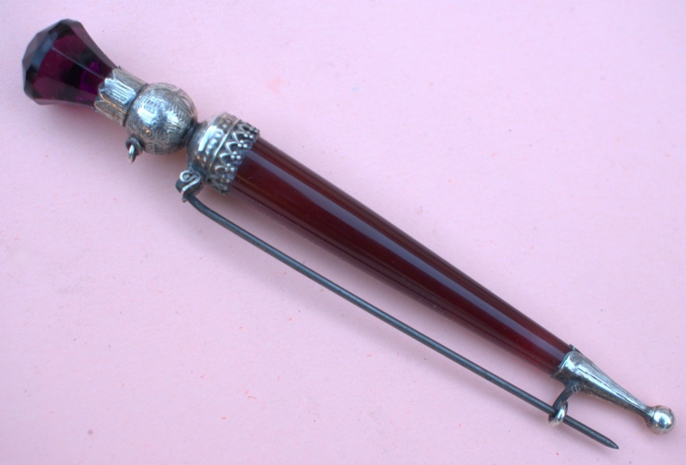 A Victorian Scottish silver and red agate dirk brooch shaped like a dagger with engraved thistle details and a faceted purple stone pommel. View II