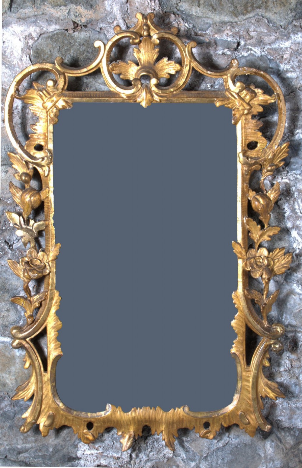 A small George III carved giltwood wall mirror featuring pierced scrolling acanthus leaves, floral motifs, and a rectangular central glass pane.