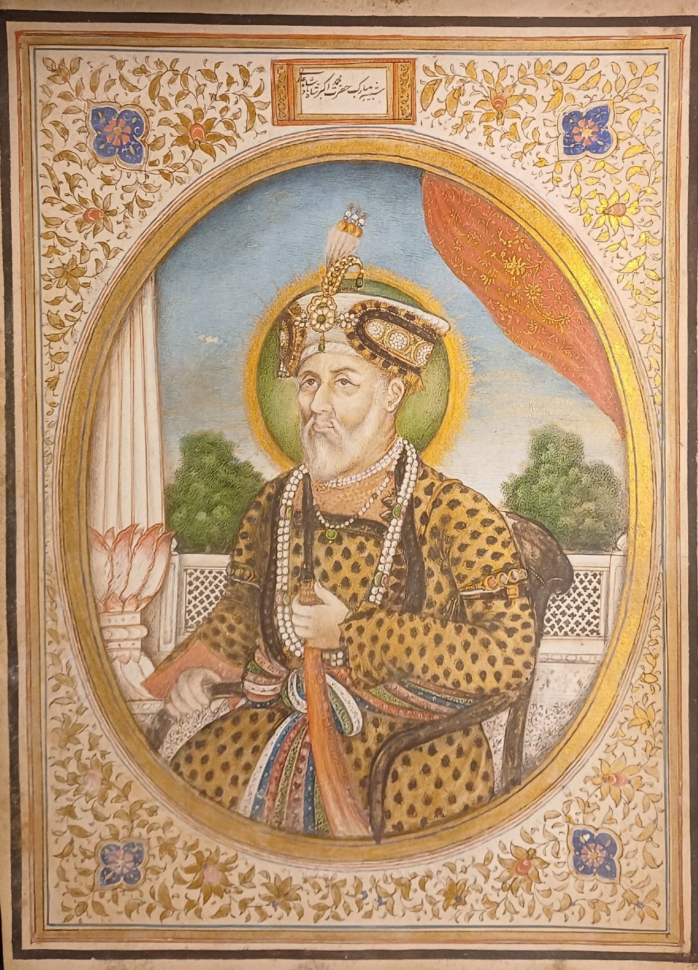 An oval portrait miniature painting of Mughal Emperor Akbar II wearing a jewelled turban, set within an illuminated floral border and a gilded wooden frame. View III