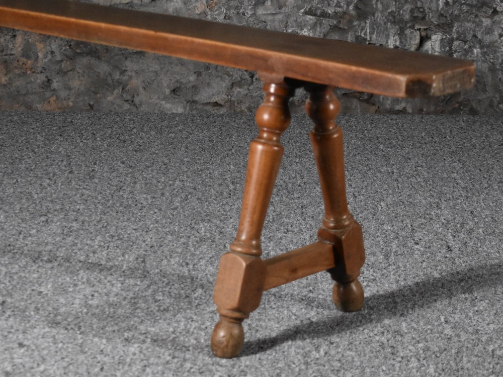 A pair of long 19th-century cherry wood benches with turned trestle legs, stretchers, and smooth timber tops. View III
