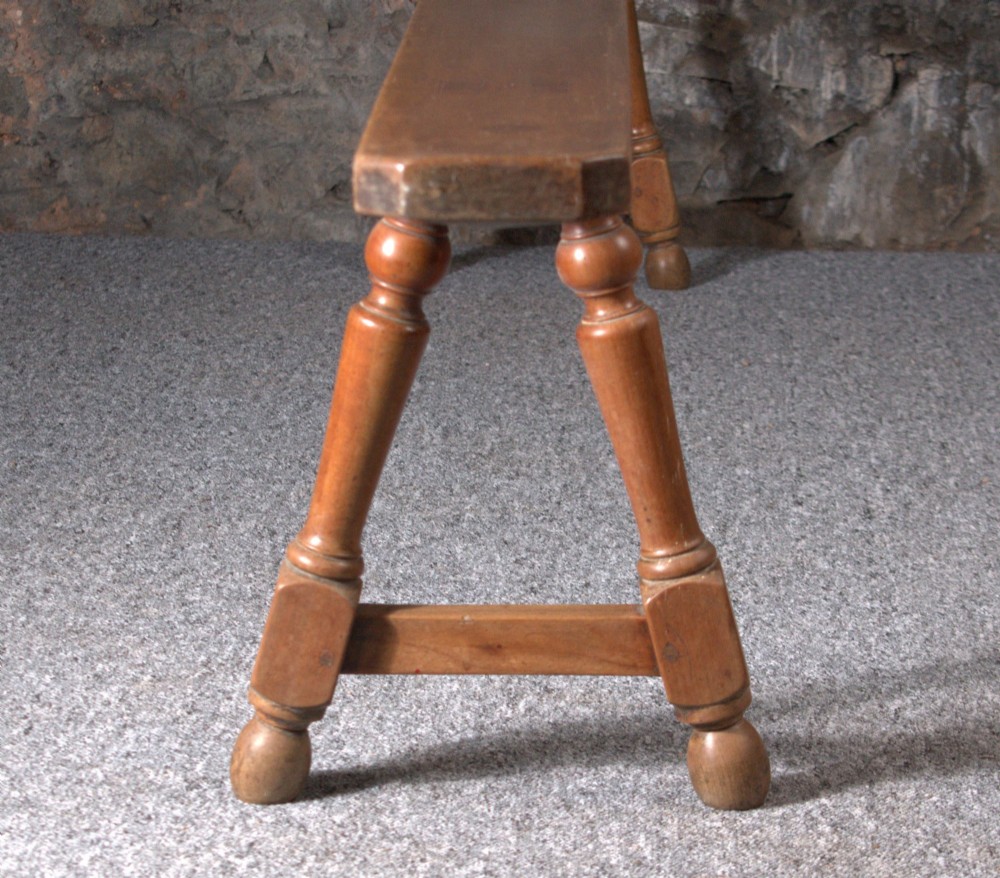 A pair of long 19th-century cherry wood benches with turned trestle legs, stretchers, and smooth timber tops. View VI