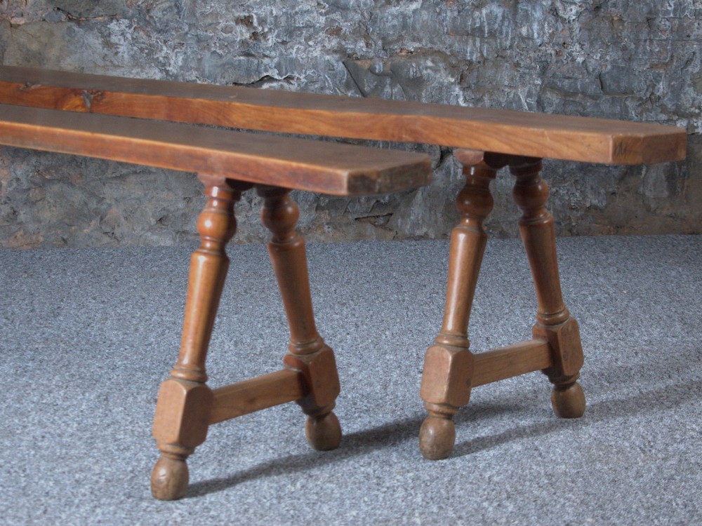 A pair of long 19th-century cherry wood benches with turned trestle legs, stretchers, and smooth timber tops. View VIII