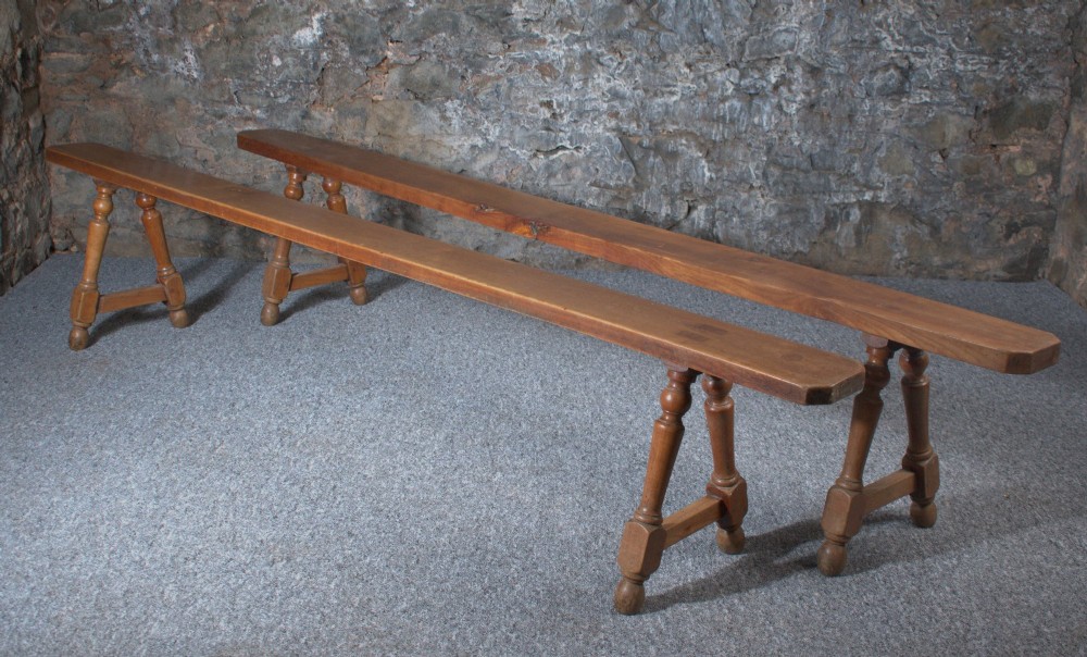 A pair of long 19th-century cherry wood benches with turned trestle legs, stretchers, and smooth timber tops. View IX
