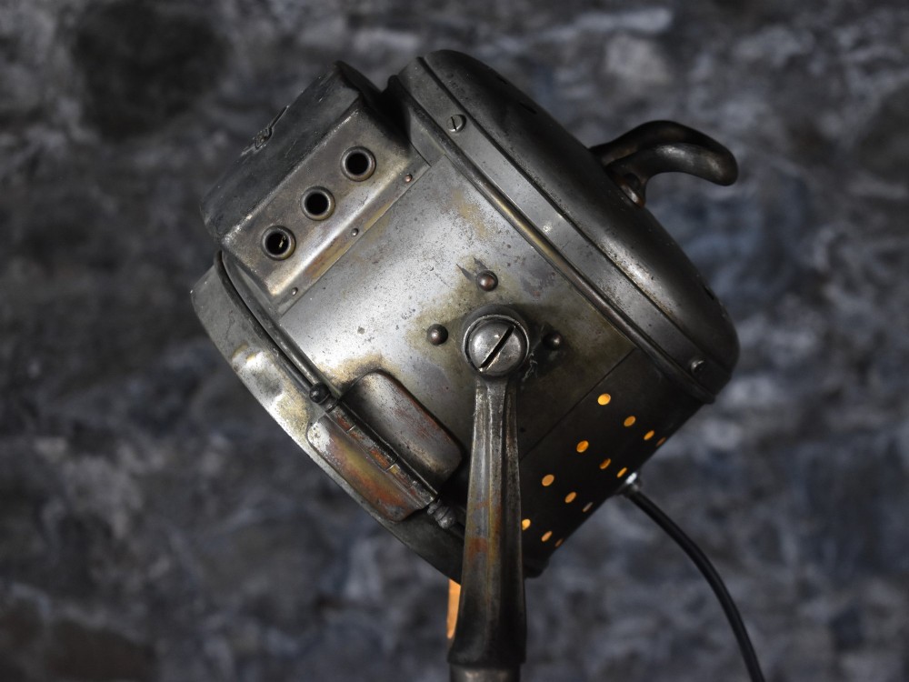 An early 20th-century Bleriot metal searchlight mounted on an adjustable dark metal telescoping floor stand with a cast tripod base. View III