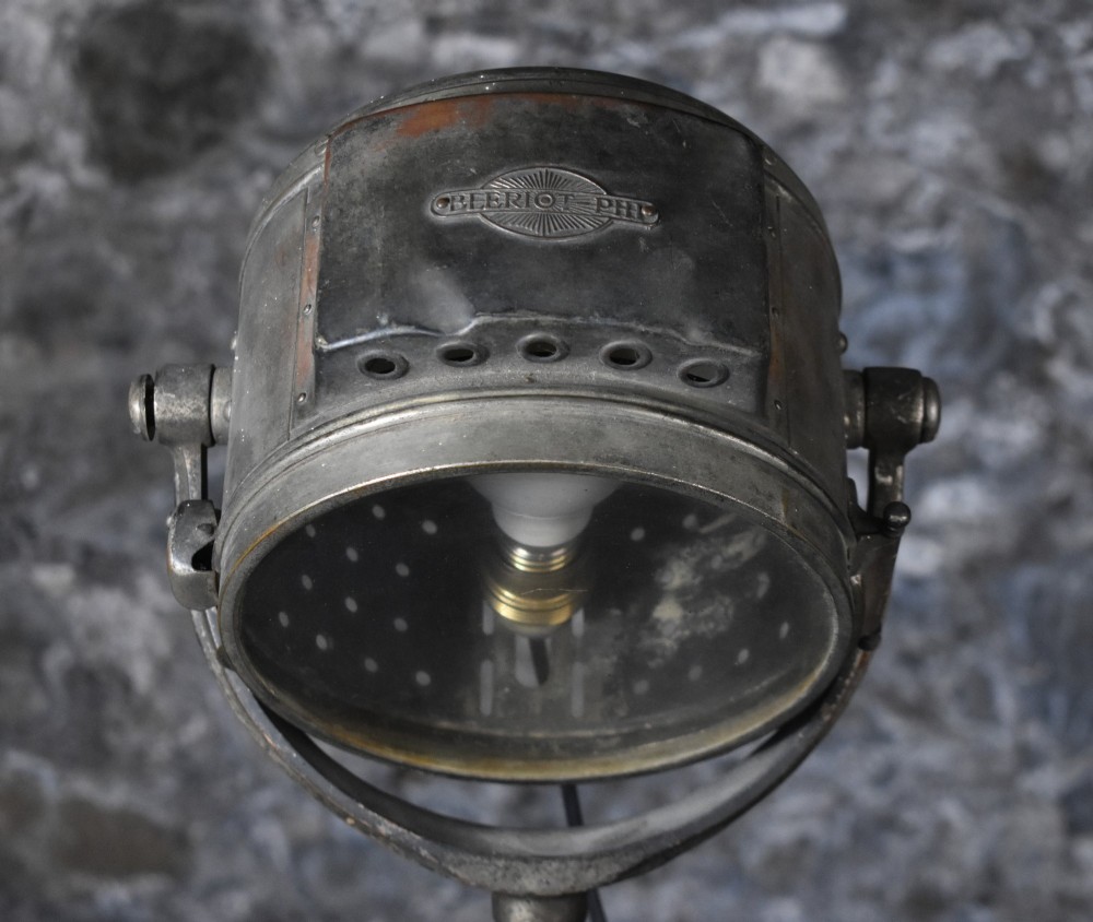 An early 20th-century Bleriot metal searchlight mounted on an adjustable dark metal telescoping floor stand with a cast tripod base. View V