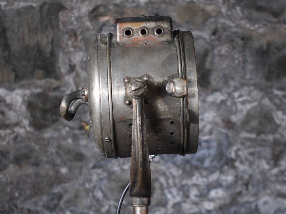 An early 20th-century Bleriot metal searchlight mounted on an adjustable dark metal telescoping floor stand with a cast tripod base. View VII