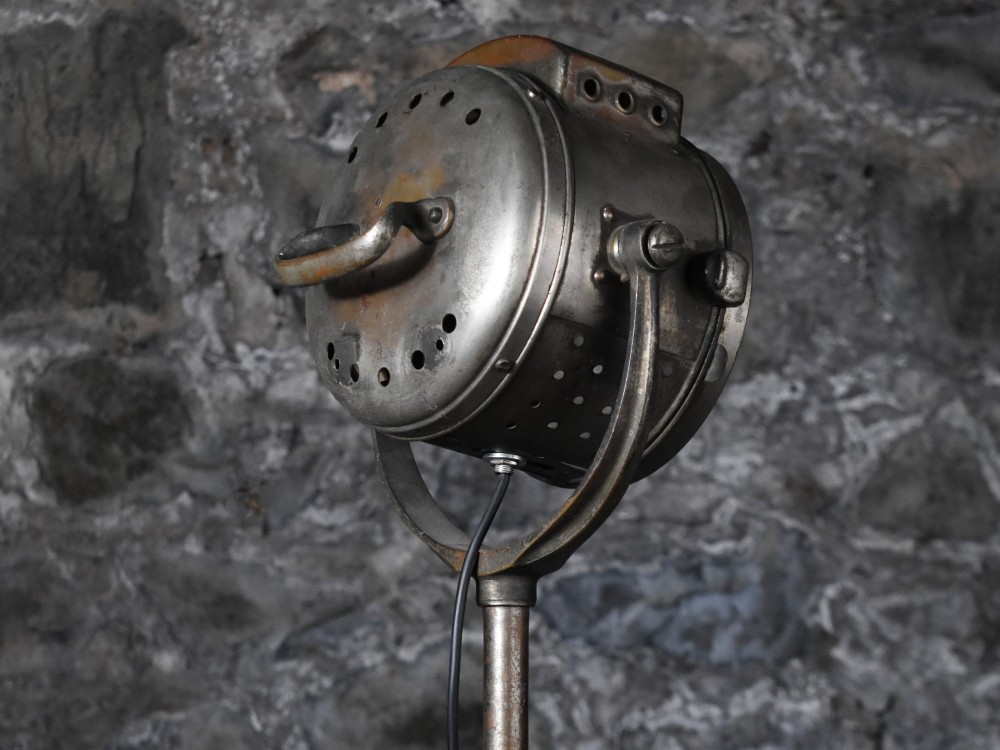 An early 20th-century Bleriot metal searchlight mounted on an adjustable dark metal telescoping floor stand with a cast tripod base. View VIII