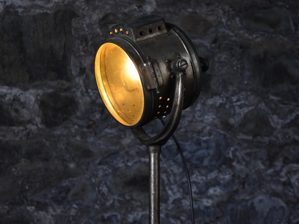 An early 20th-century Bleriot metal searchlight mounted on an adjustable dark metal telescoping floor stand with a cast tripod base. View II