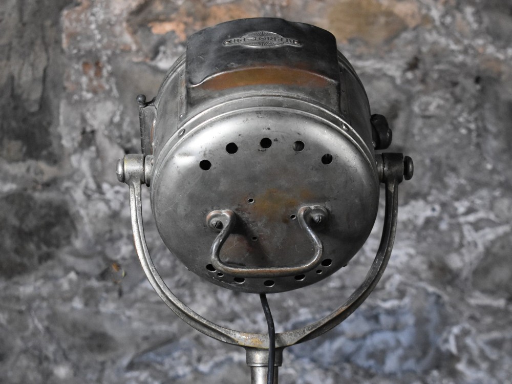 An early 20th-century Bleriot metal searchlight mounted on an adjustable dark metal telescoping floor stand with a cast tripod base. View IX