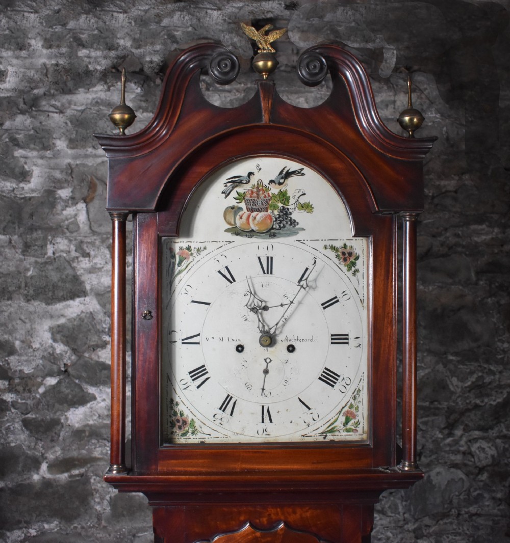 A George III flame mahogany longcase clock featuring a swan-neck pediment with brass finials and an arched painted dial with Roman numerals. View II