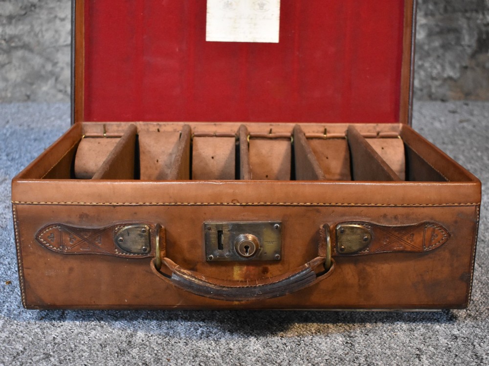 Late 19th-century tan leather cartridge case featuring an oak core, double leather straps, central brass lock, and stitched carrying handle. View VI