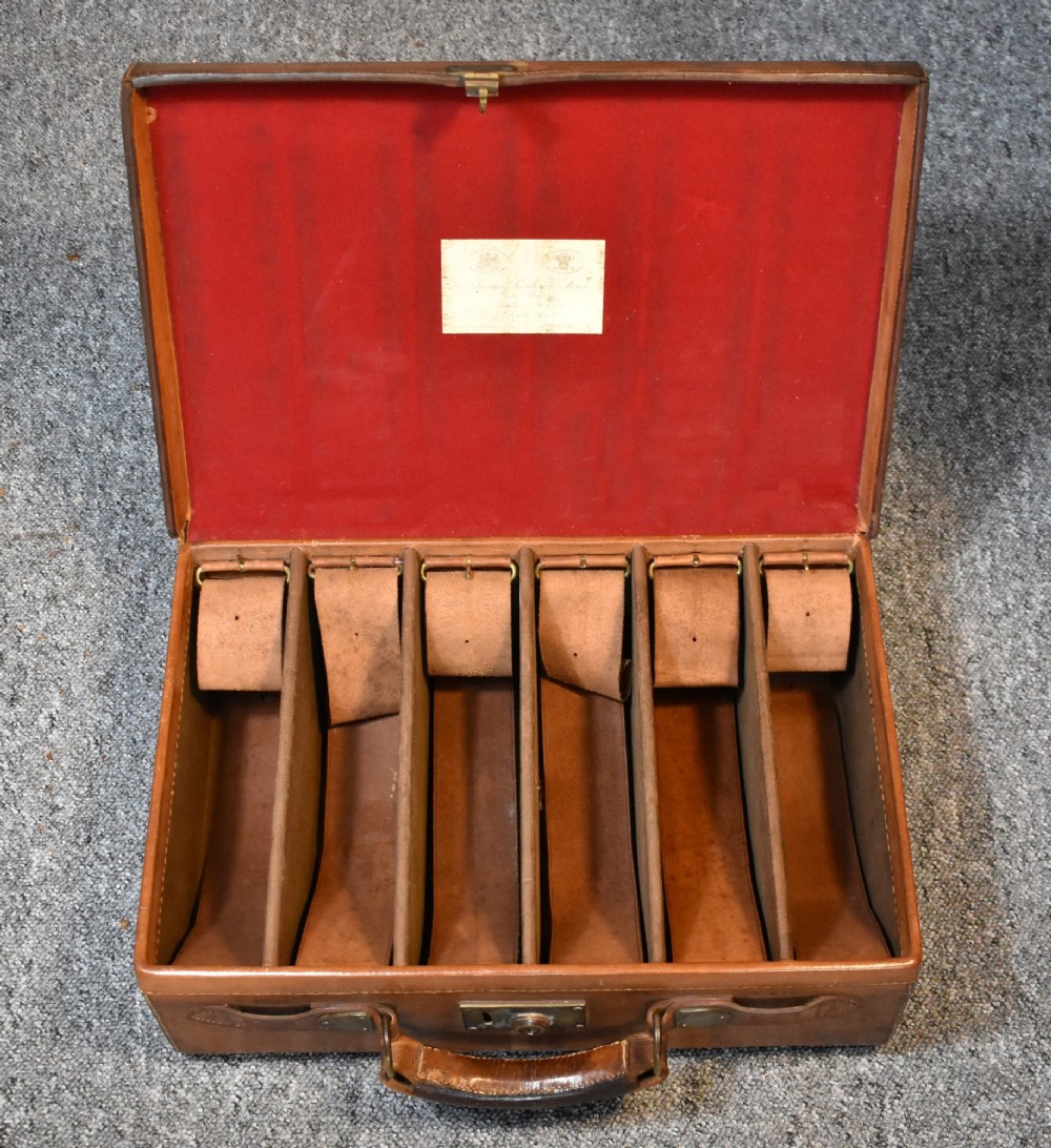 Late 19th-century tan leather cartridge case featuring an oak core, double leather straps, central brass lock, and stitched carrying handle. View VIII