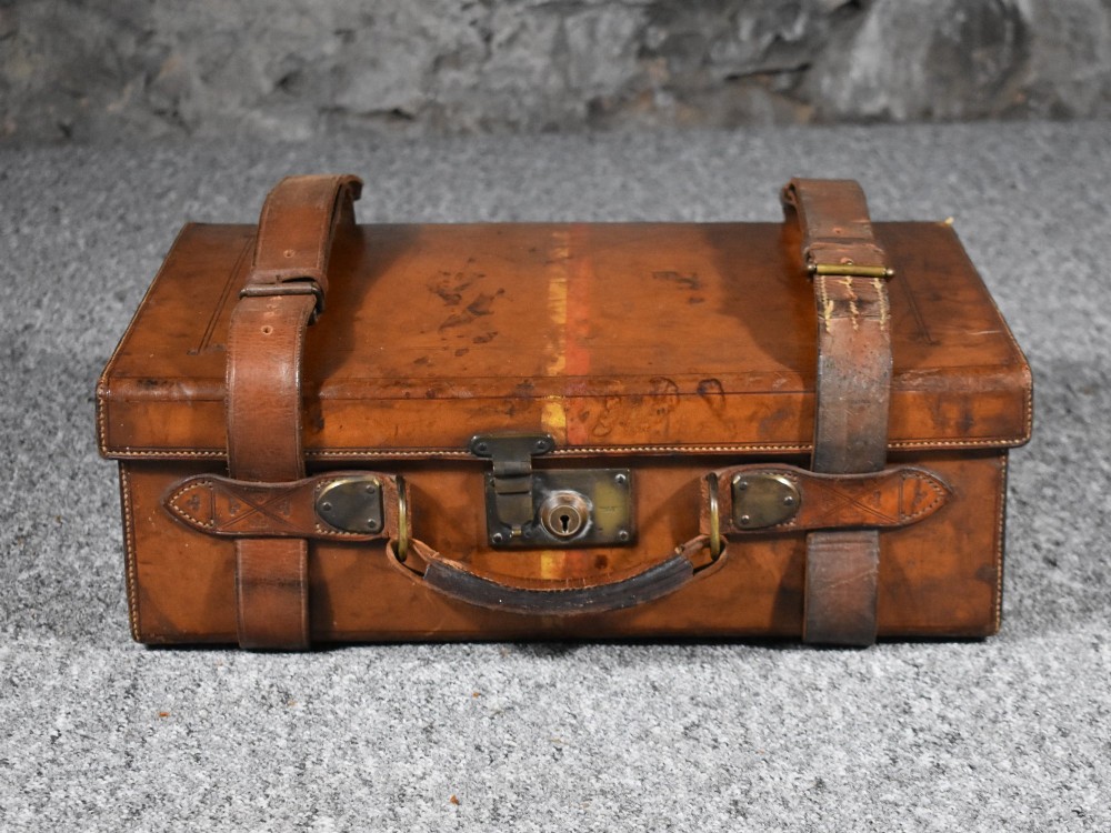 Late 19th-century tan leather cartridge case featuring an oak core, double leather straps, central brass lock, and stitched carrying handle.