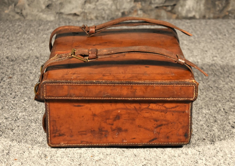 Late 19th-century tan leather cartridge case featuring an oak core, double leather straps, central brass lock, and stitched carrying handle. View X