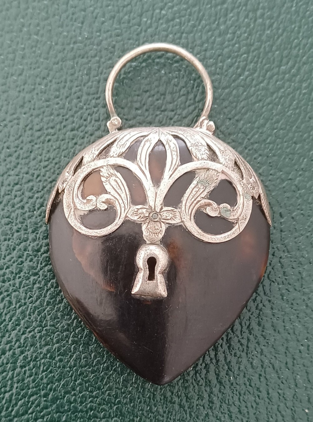A Victorian heart-shaped tortoiseshell pendant featuring ornate silver scrollwork mounting and a keyhole motif with a top hanging loop.