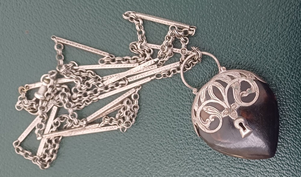 A Victorian heart-shaped tortoiseshell pendant featuring ornate silver scrollwork mounting and a keyhole motif with a top hanging loop. View IV