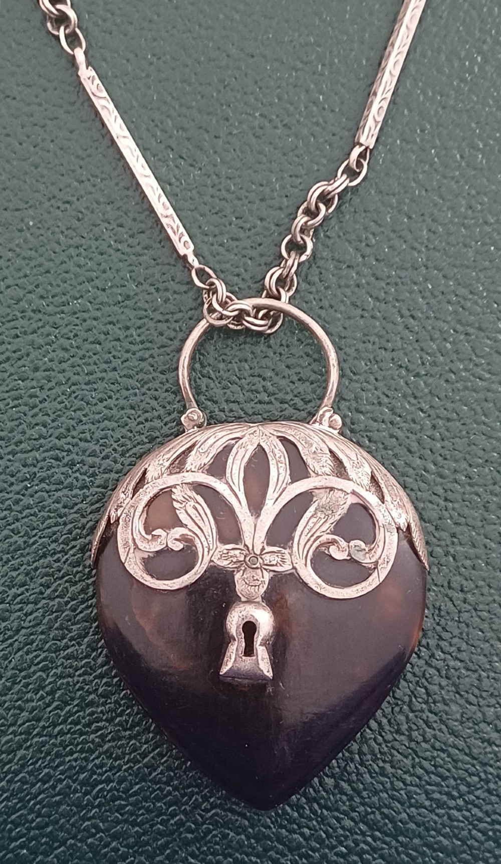 A Victorian heart-shaped tortoiseshell pendant featuring ornate silver scrollwork mounting and a keyhole motif with a top hanging loop. View II
