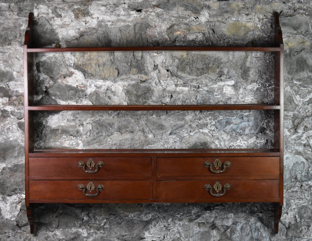 A George III mahogany wall-mounted shelf unit featuring three open display tiers set above four drawers with brass swan-neck handles. View II