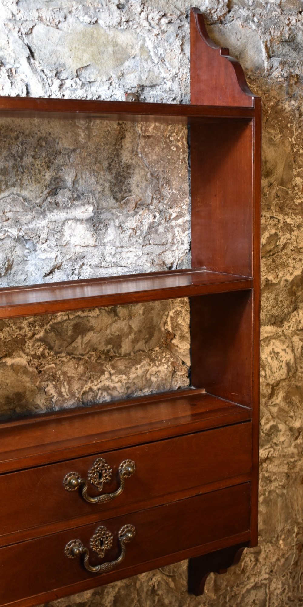 A George III mahogany wall-mounted shelf unit featuring three open display tiers set above four drawers with brass swan-neck handles. View V