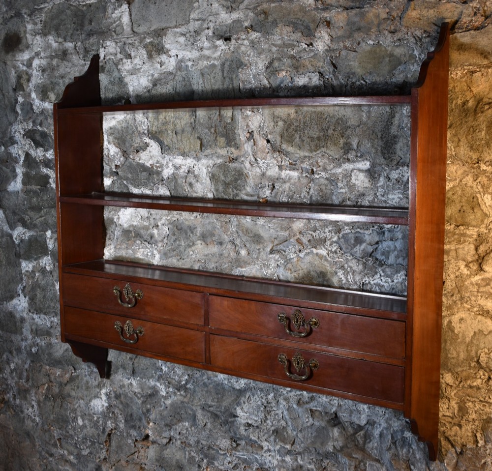 A George III mahogany wall-mounted shelf unit featuring three open display tiers set above four drawers with brass swan-neck handles. View VII