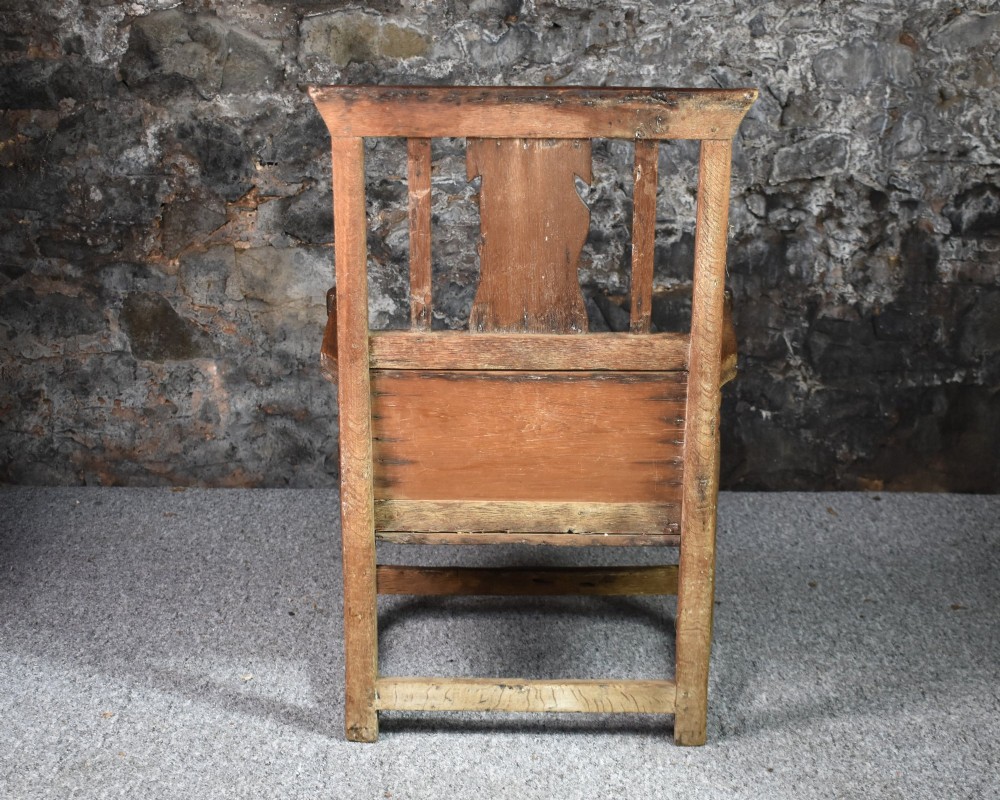 An 18th-century Scottish crofter armchair featuring turned front arm posts, panelled sides, and a slatted back in a warm wood finish. View V