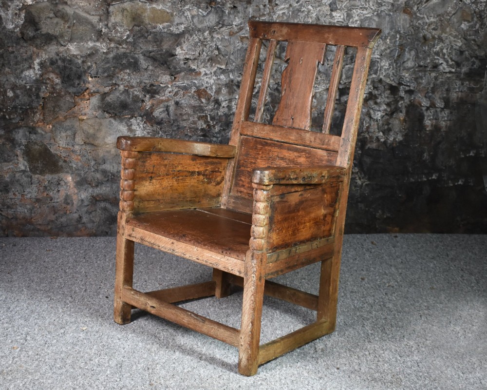 An 18th-century Scottish crofter armchair featuring turned front arm posts, panelled sides, and a slatted back in a warm wood finish. View VI