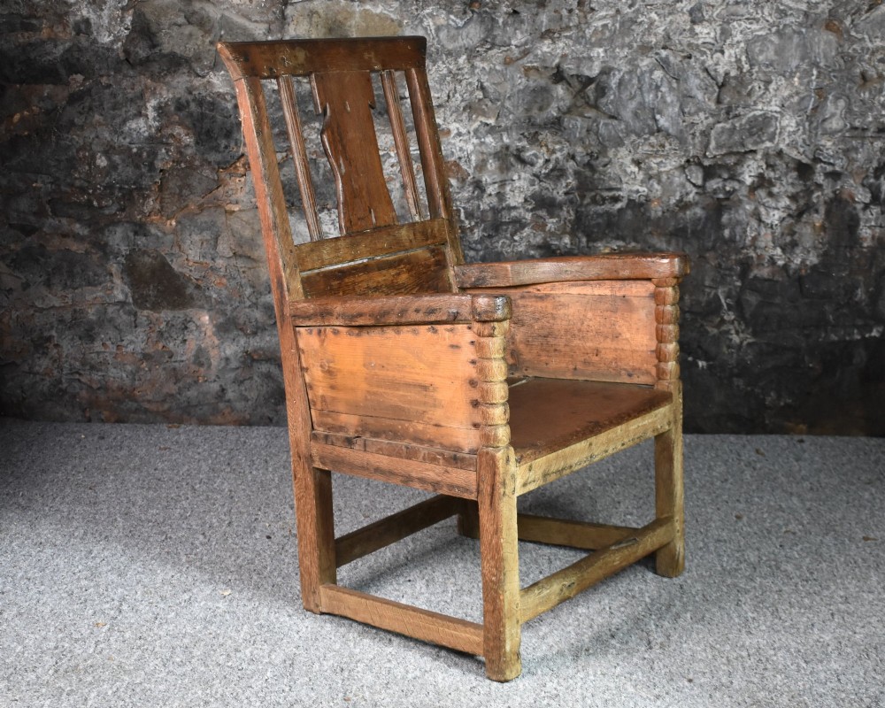 An 18th-century Scottish crofter armchair featuring turned front arm posts, panelled sides, and a slatted back in a warm wood finish. View VII