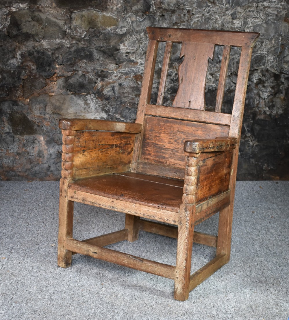 An 18th-century Scottish crofter armchair featuring turned front arm posts, panelled sides, and a slatted back in a warm wood finish. View IX
