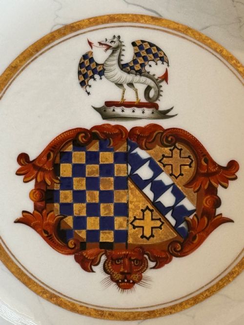 fig 1. An antique circular porcelain soup plate featuring a central heraldic coat of arms, a faux marble pattern on the rim, and decorative gilded borders.