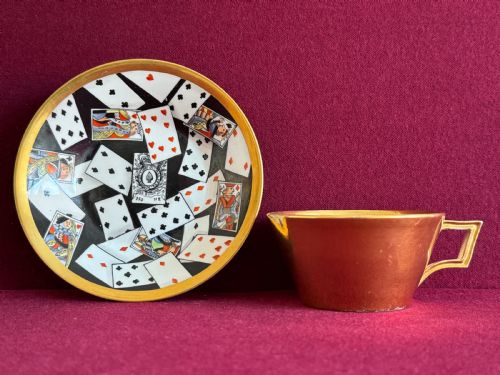 fig 2. An antique Regency period porcelain teacup and matching saucer featuring a hand-painted playing card motif on the interior and a gilded exterior finish.