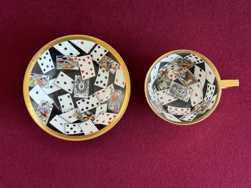 fig 1. An antique Regency period porcelain teacup and matching saucer featuring a hand-painted playing card motif on the interior and a gilded exterior finish.