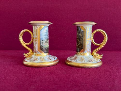 fig 1. A pair of early nineteenth-century porcelain candlesticks featuring hand-painted landscape scenes on the shafts and detailed gilding on the bases.