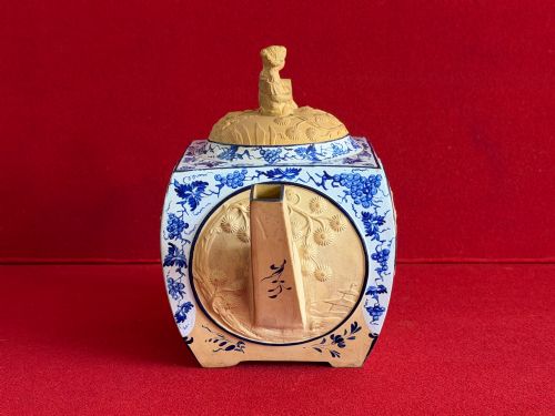 fig 1. An eighteenth-century box-shaped Spode caneware teapot with moulded Chinoiserie relief panels, blue foliage borders, and a reclining figural lid finial.