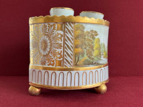 fig 1. An antique Georgian porcelain bough pot decorated with a hand-painted landscape panel, gilded geometric scroll patterns, arch motifs, and gilt ball feet.