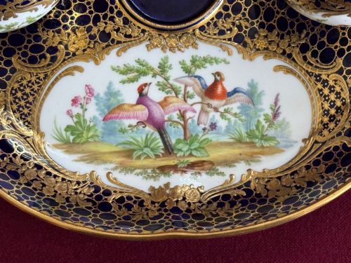 fig 1. An oval cobalt blue porcelain inkstand decorated with gold honeycomb diapering, hand-painted bird cartouches, and two covered inkwells with gilt branch handles.