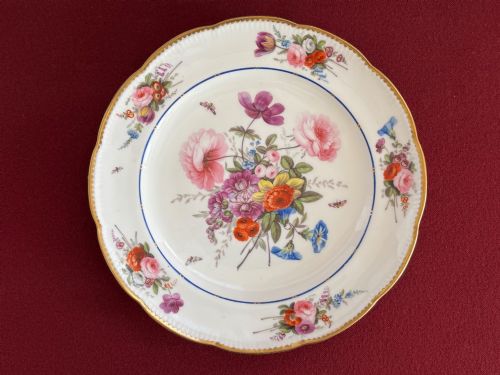 fig 1. A pair of circular white Regency porcelain plates with lobed gilded rims and hand-painted floral bouquets at the centre and border.