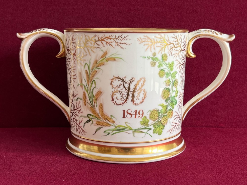 A Victorian English porcelain loving cup featuring two gilded scroll handles and a hand-painted hound named Drummer in a rural setting. View II