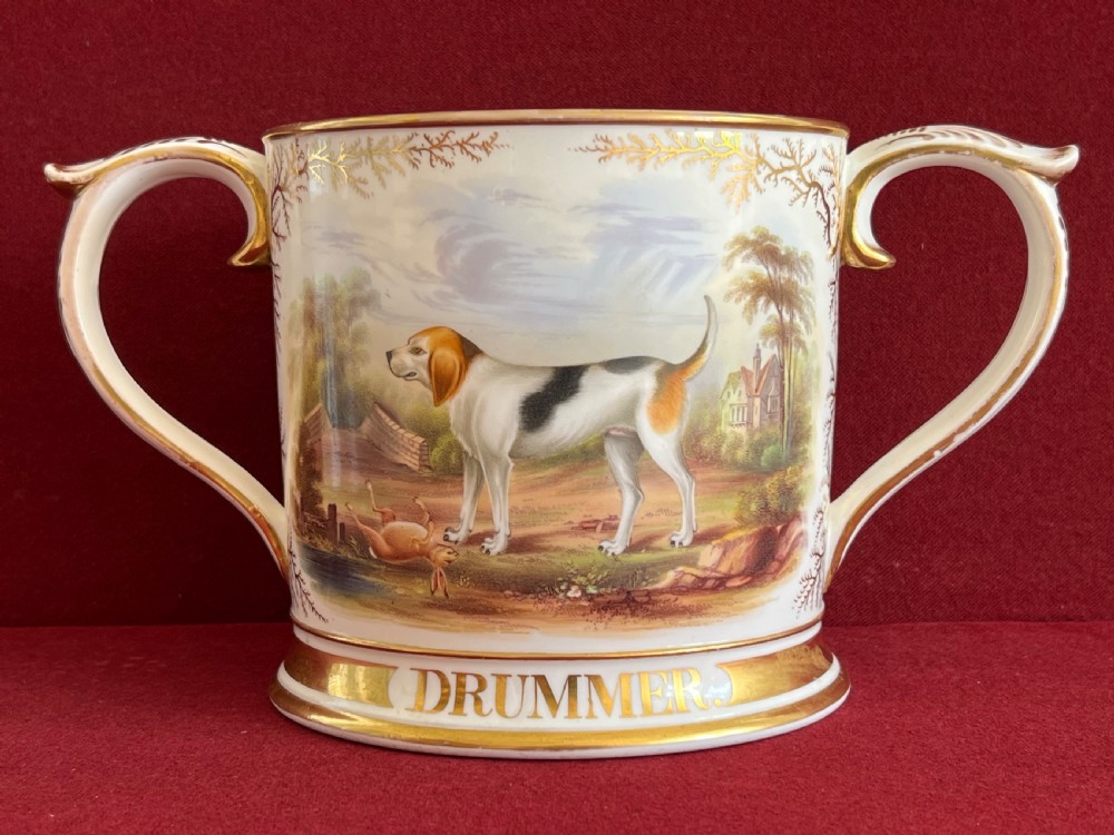 A Victorian English porcelain loving cup featuring two gilded scroll handles and a hand-painted hound named Drummer in a rural setting. View III