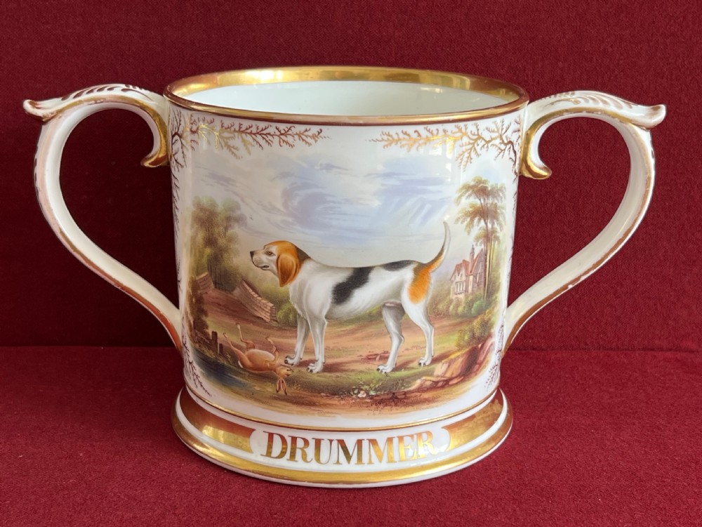 A Victorian English porcelain loving cup featuring two gilded scroll handles and a hand-painted hound named Drummer in a rural setting. View VII