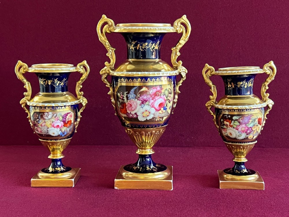 A three-piece English cobalt blue and gilded porcelain garniture set decorated with floral panels.