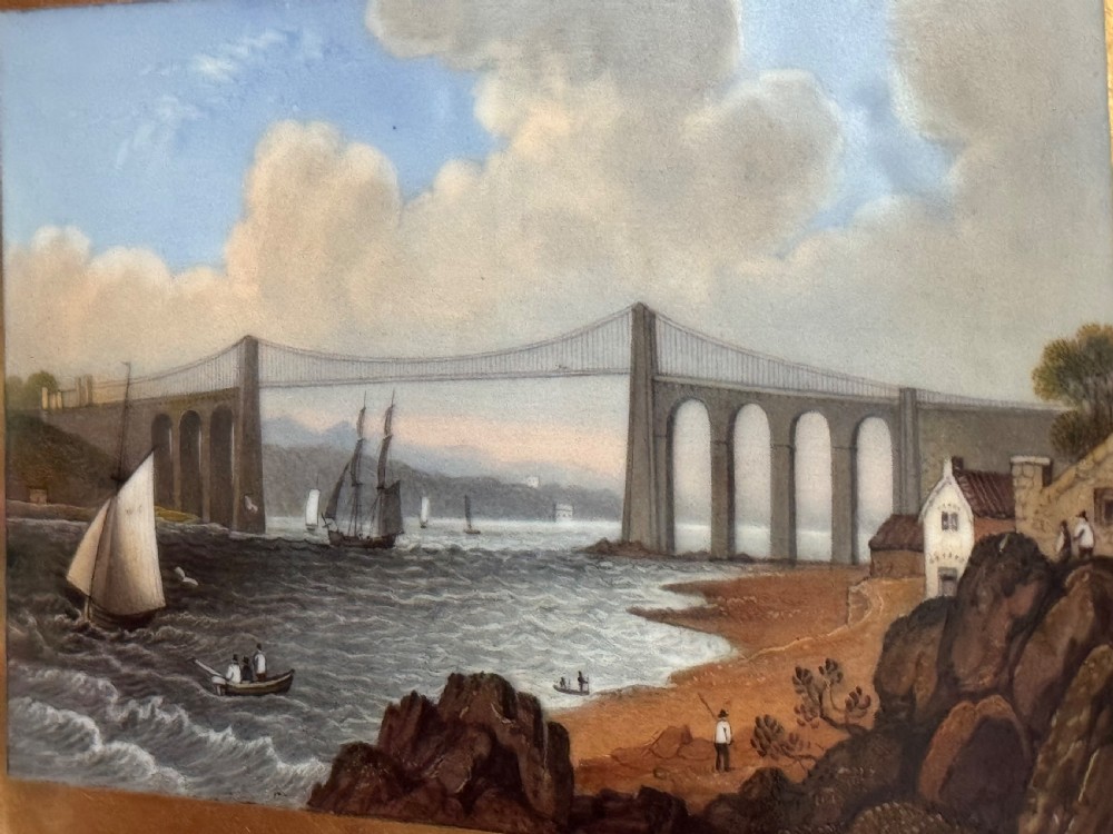 An antique rectangular porcelain basket with an overhead handle, decorated with three-dimensional applied shells along the rim and a hand-painted central view of the Menai Bridge on a cobalt blue dotted background. View III