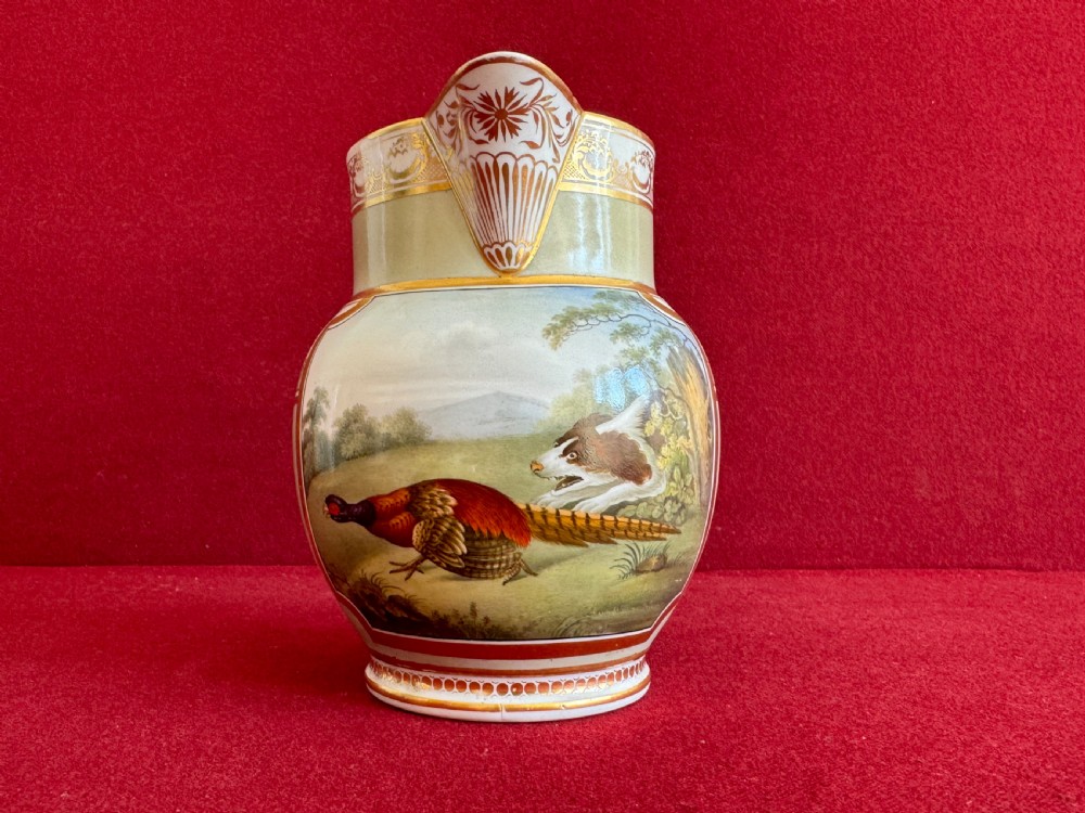 A Regency period Chamberlain Worcester porcelain jug decorated with a hand-painted scene of a dog and pheasant set within a landscape and detailed with gilded borders.