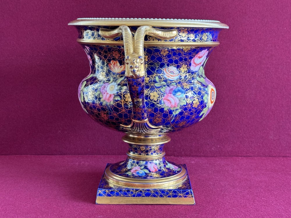 A cobalt blue Regency porcelain Warwick-style urn decorated with hand-painted floral bouquets, gold gilding, twin gilded handles, and a square pedestal base. View IV
