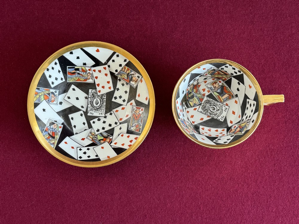 An antique Regency period porcelain teacup and matching saucer featuring a hand-painted playing card motif on the interior and a gilded exterior finish. View II