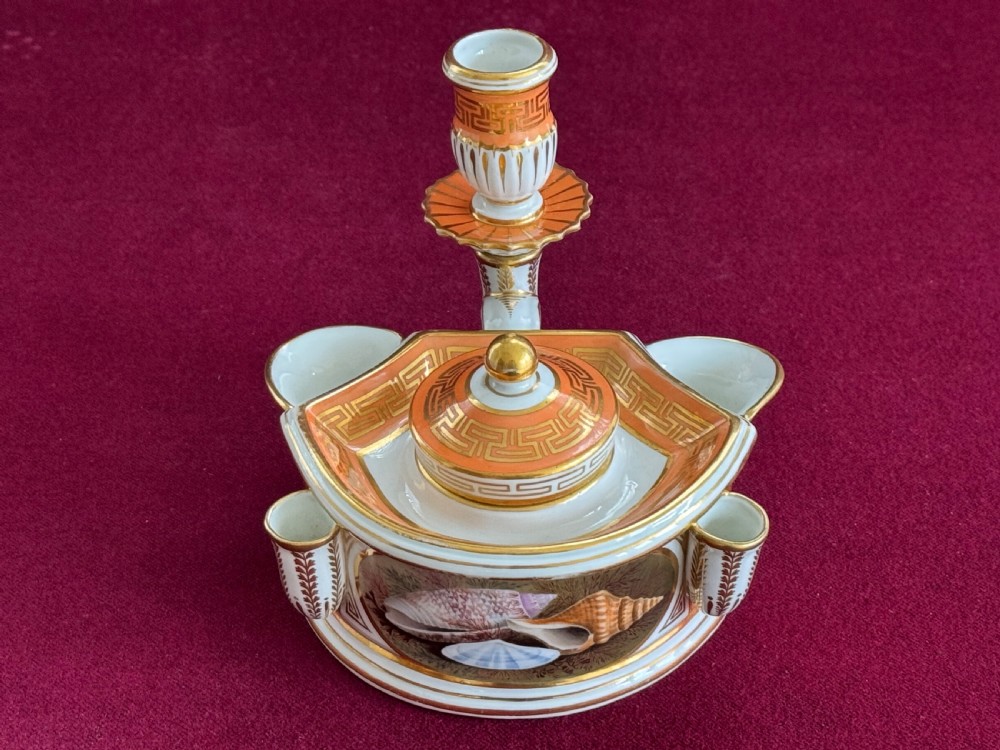 An early nineteenth-century Worcester porcelain inkstand featuring hand-painted seashell panels, orange Greek key borders, gilded accents, and a central candle sconce.