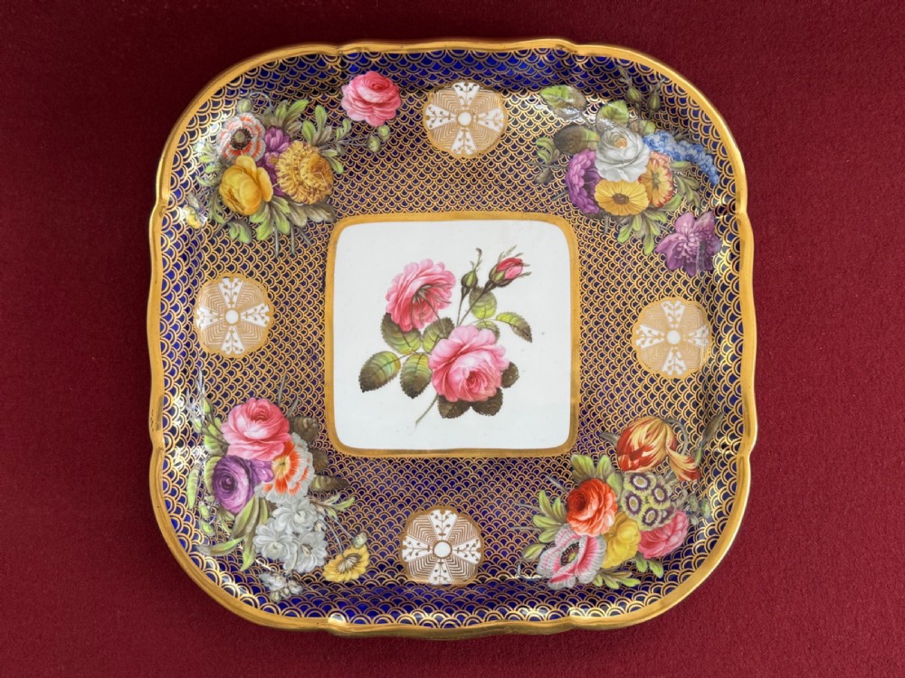 A square antique Spode porcelain tray decorated with a cobalt blue and gold scale pattern border surrounding hand-painted floral sprays and a central rose motif.
