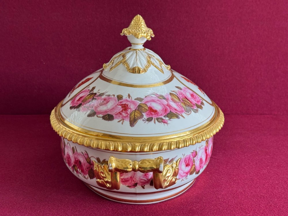 An oval Regency Worcester porcelain entree dish with a fitted lid, featuring hand-painted pink rose garlands, gilt gadrooned rims, twin gilded handles, a heraldic lion crest, and a gold leaf-and-pineapple finial. View IV